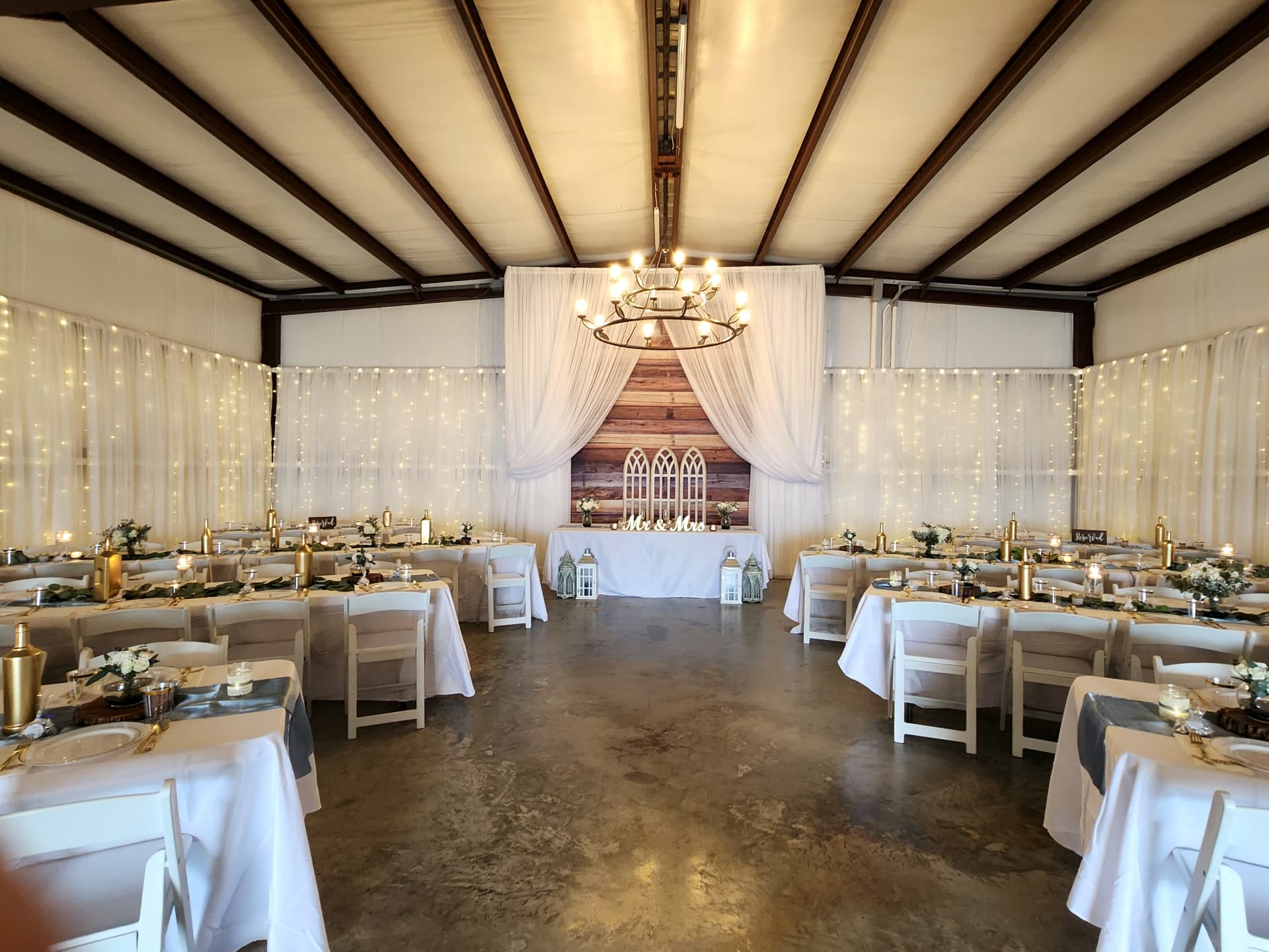 Draped barn reception with iron chandelier, Mr & Mrs sweetheart table and reclaimed wood backdrop