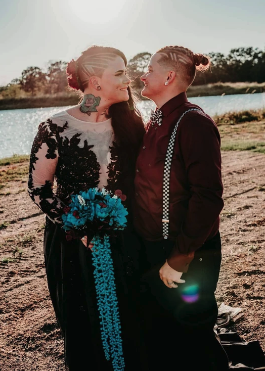 Sunlit portrait of the couple by the lake with a teal bouquet and burgundy suspenders