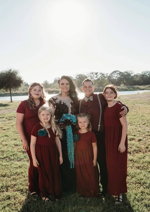 Family portrait in burgundy dresses beside the lake in bright afternoon sun