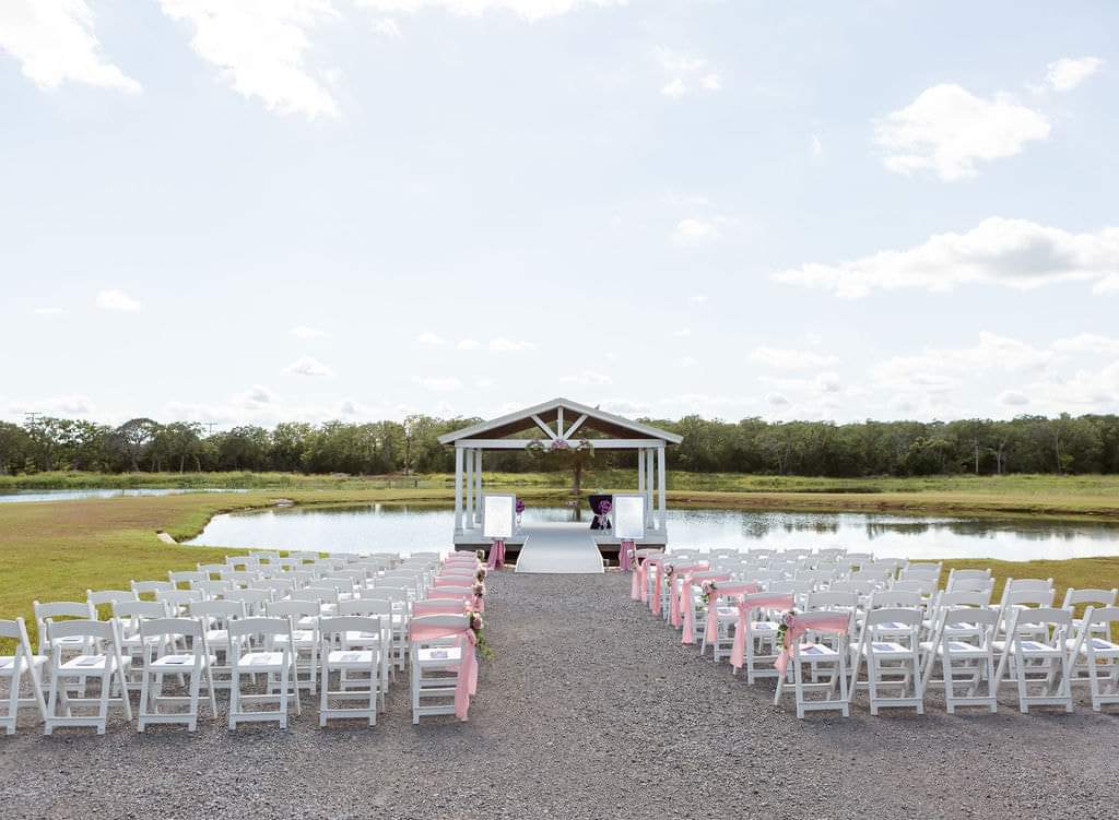 Lakeside ceremony seating with blush sashes facing the waterfront pavilion