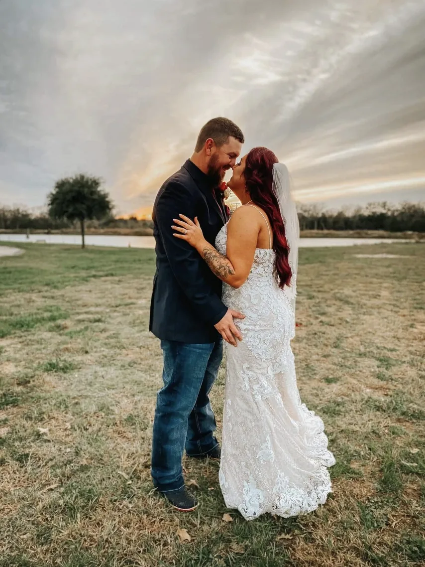 Tate and Jackie kissing at sunset beside the nine-acre lake at Reverie at Diamond D, a Texas wedding venue in Normangee