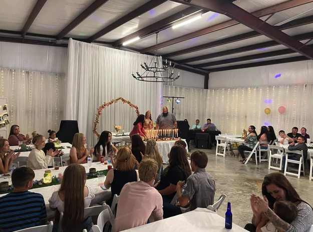 Guests applauding during the candle lighting ceremony under the iron chandelier