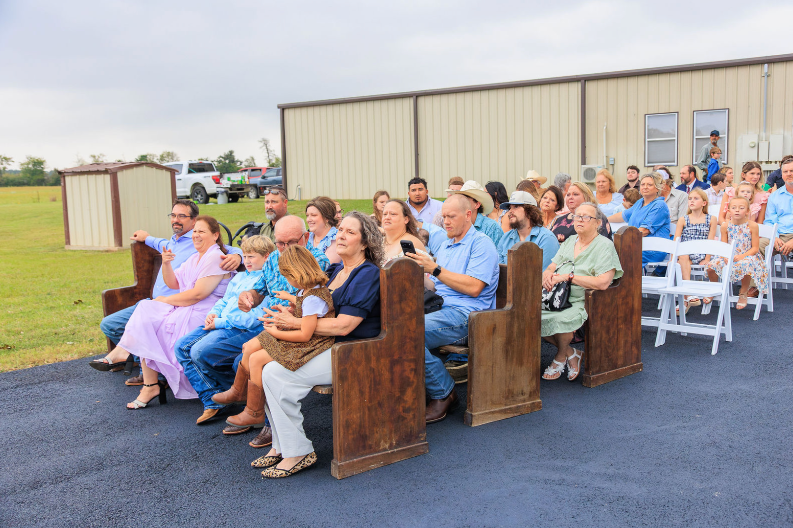 Jaelyn & Keelan's wedding at Reverie at Diamond D — guests seated on rustic wooden pews at the outdoor ceremony