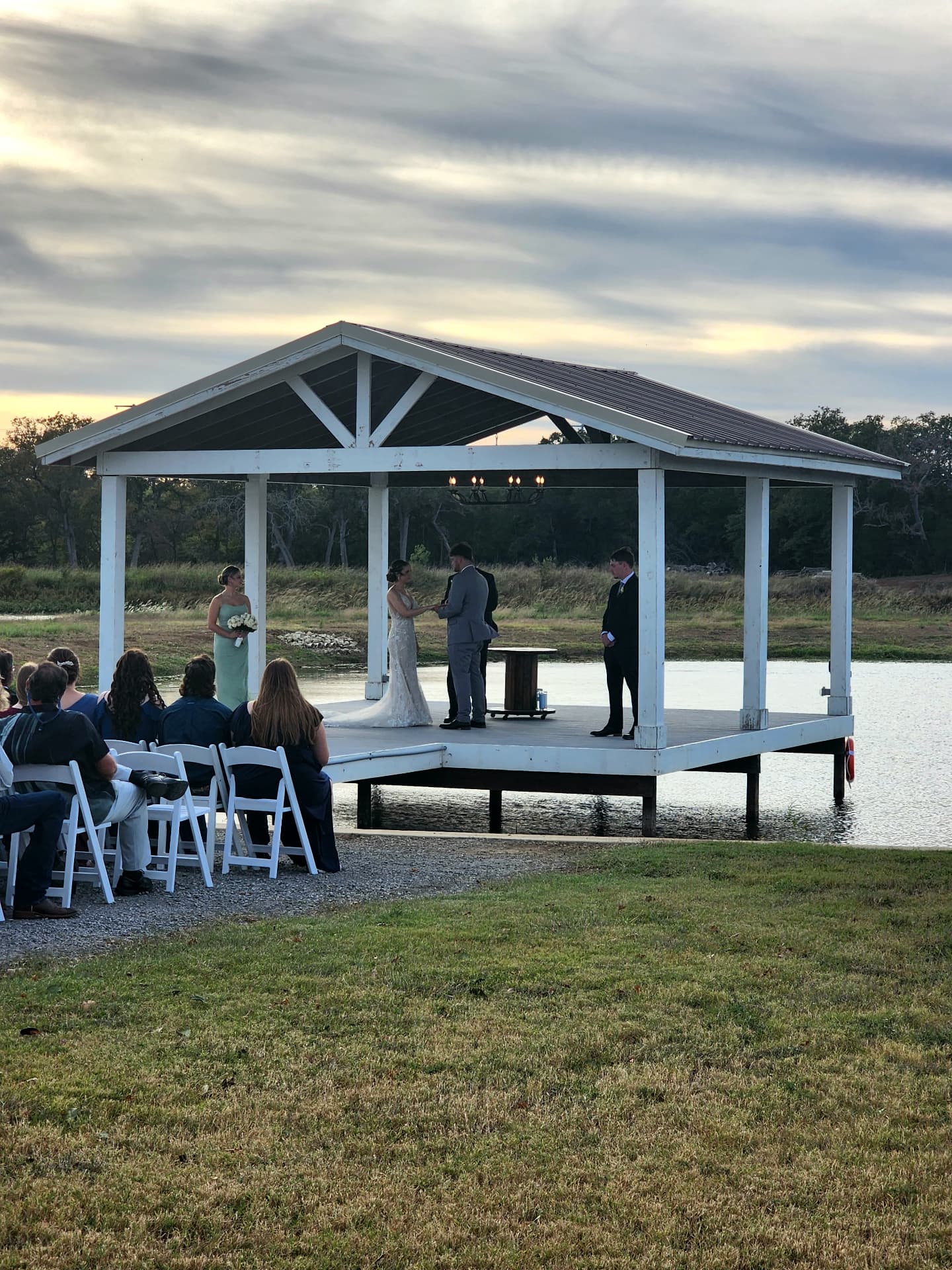 Bride and groom exchanging vows on the lakeside pavilion at golden hour at Reverie at Diamond D