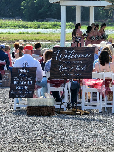 Welcome and 'pick a seat, not a side' signs at a lakeside ceremony at Reverie at Diamond D
