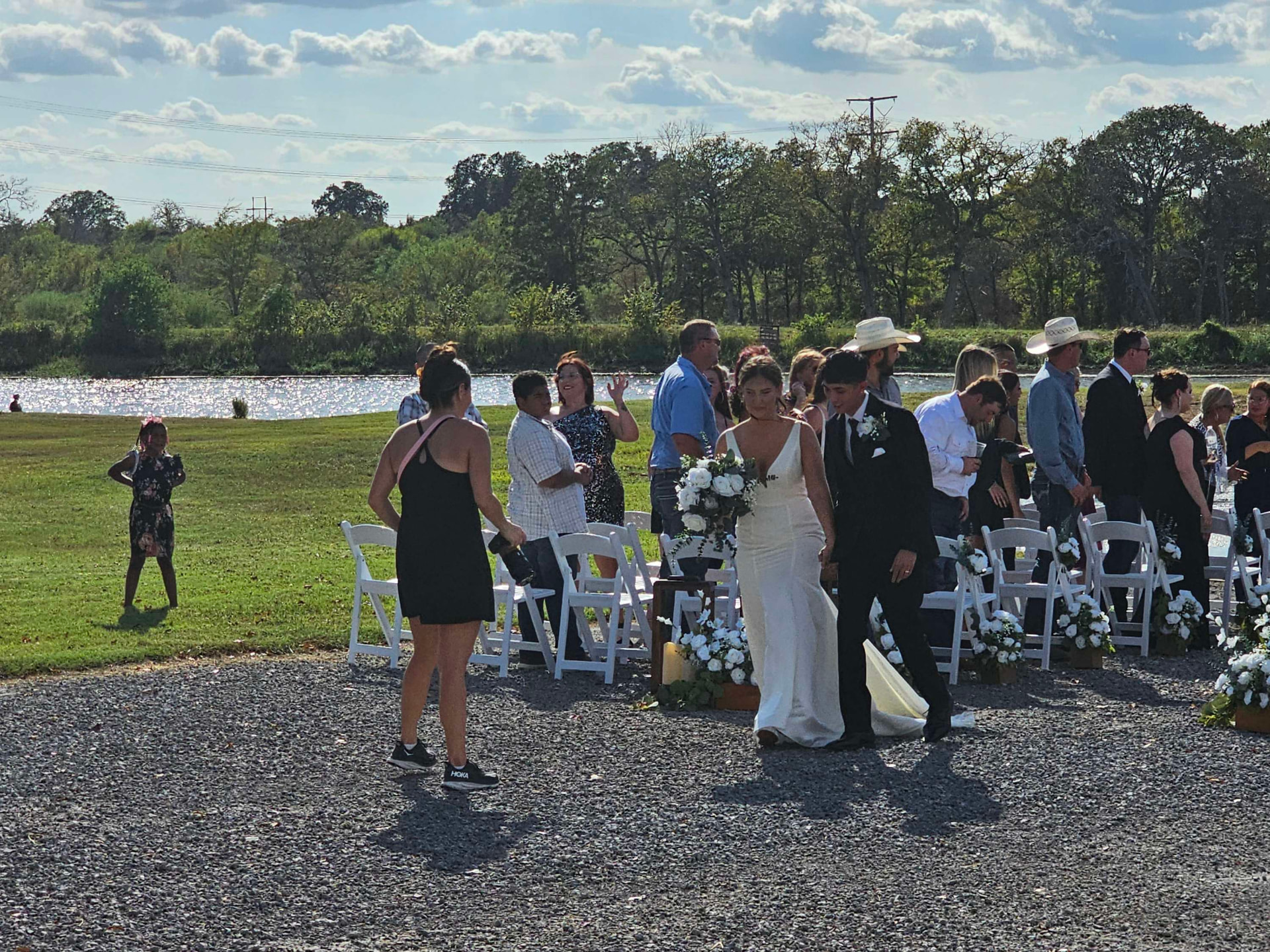Bride and groom walking back down the aisle past guests after their lakeside ceremony at Reverie at Diamond D