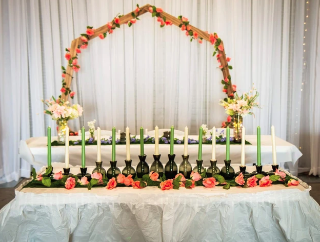 Candle lighting ceremony table with coral florals and a wooden arch backdrop in the draped hall