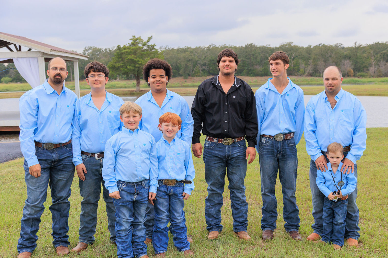 Jaelyn & Keelan's wedding at Reverie at Diamond D — the groom with his groomsmen and ring bearers on the lawn by the lake