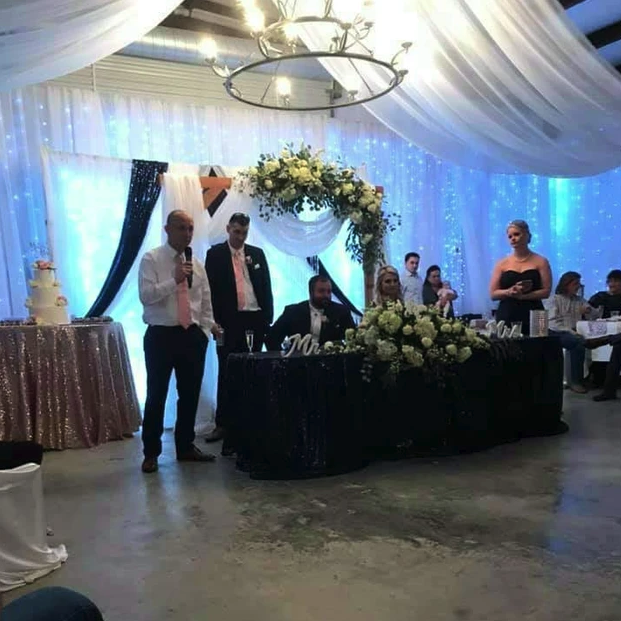 Wedding toasts at the navy sequin sweetheart table beneath the antler chandelier