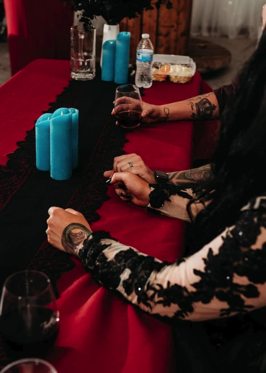 Sweetheart table with red linens, black lace runner and turquoise pillar candles