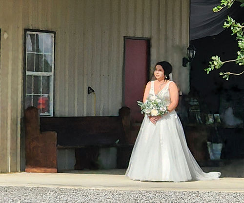 Bride in a full tulle gown waiting on the barn porch before her ceremony at Reverie at Diamond D