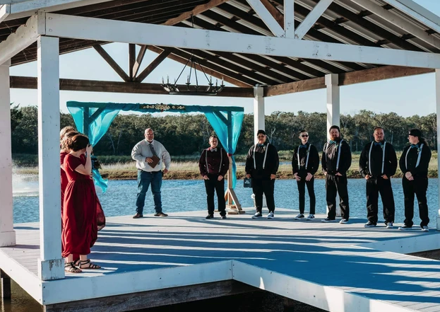 Groom's party waiting on the dock beneath the teal draped arbor before the processional