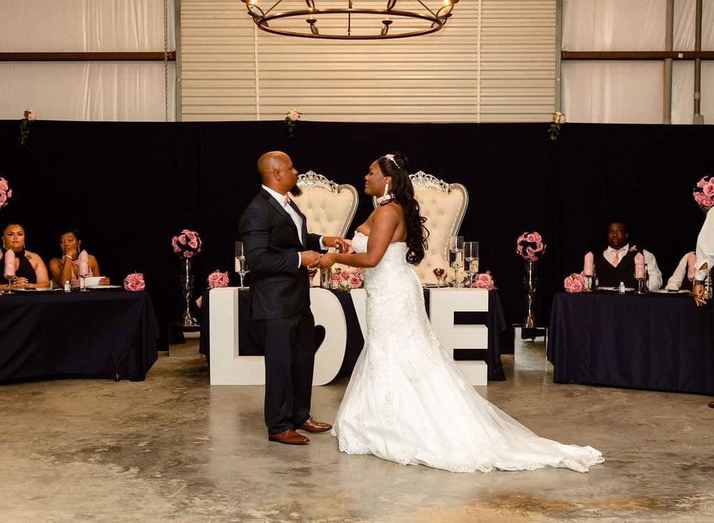 Bride and groom dancing in front of the throne chairs and navy head table