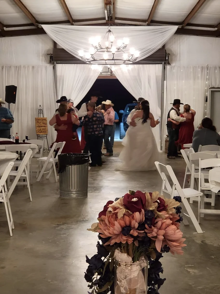 Couples dancing under the chandelier in the white draped reception hall at a Texas country wedding