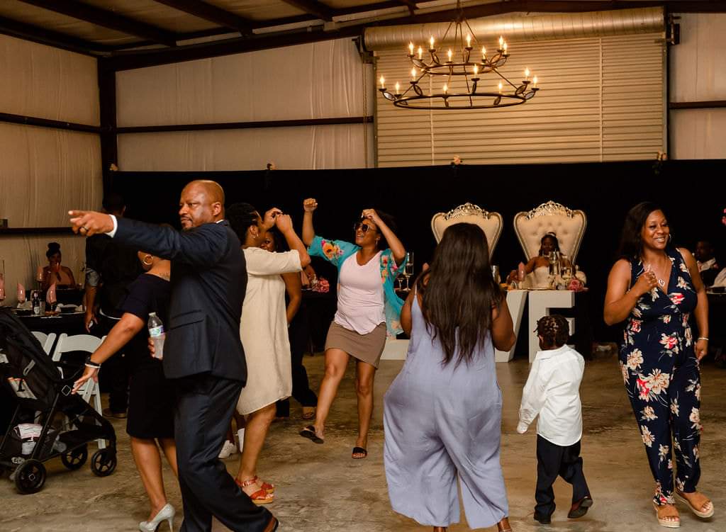 Guests filling the barn dance floor beneath the iron chandelier