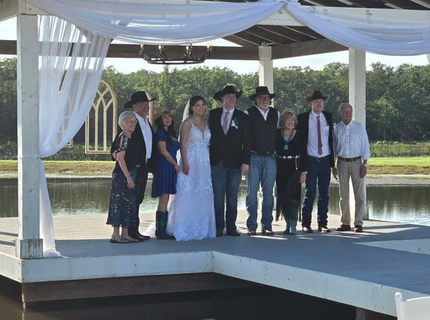 Bride, groom and family posing together on the lakeside pavilion after a 2024 wedding at Reverie at Diamond D