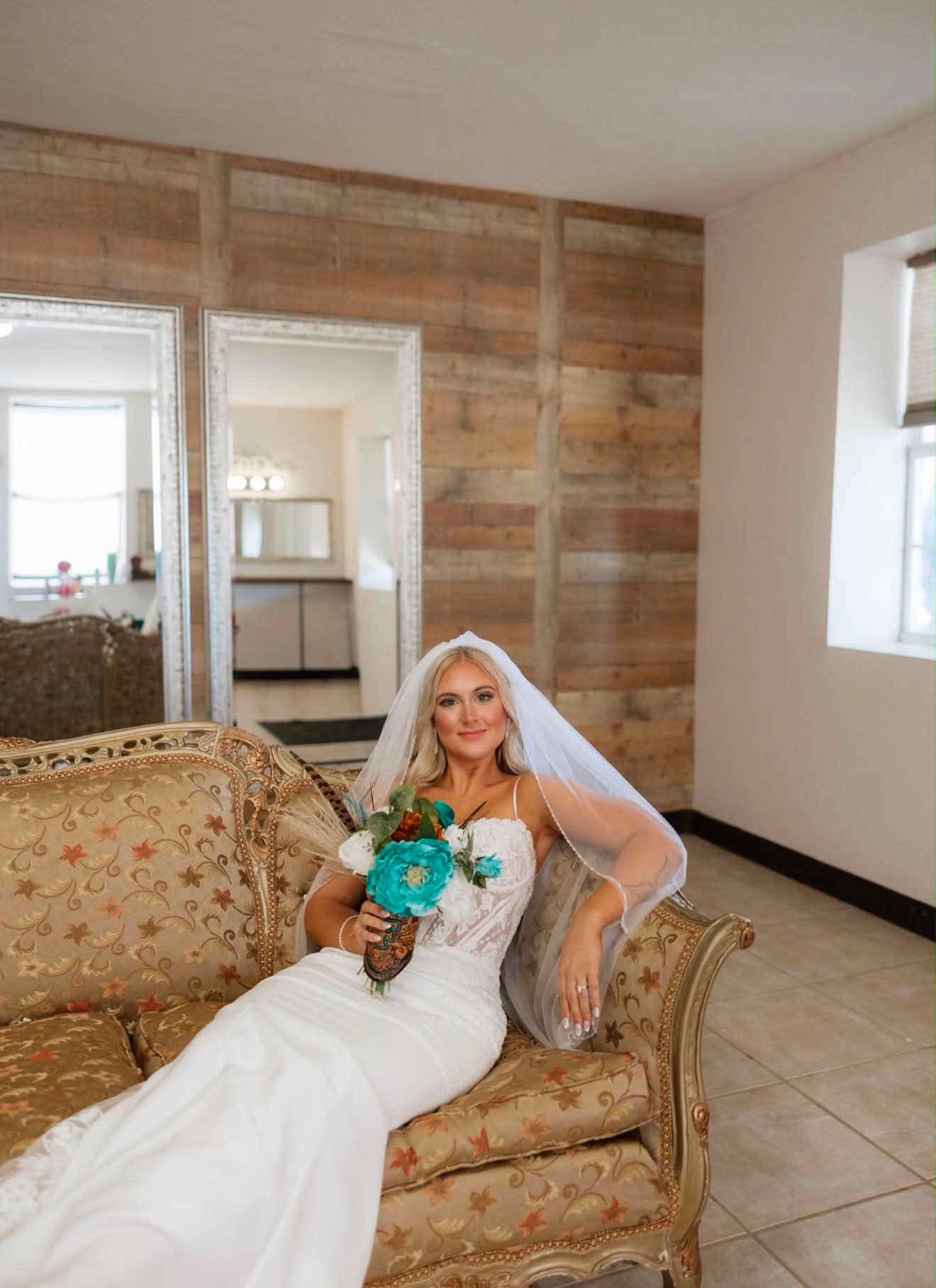 Bride relaxing on a vintage gold settee in the bridal suite at Reverie at Diamond D in Normangee, Texas
