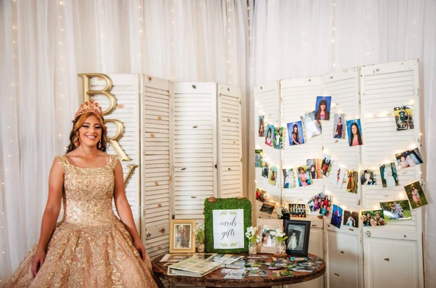 Sweet 16 honoree beside the lighted photo display and cards and gifts table