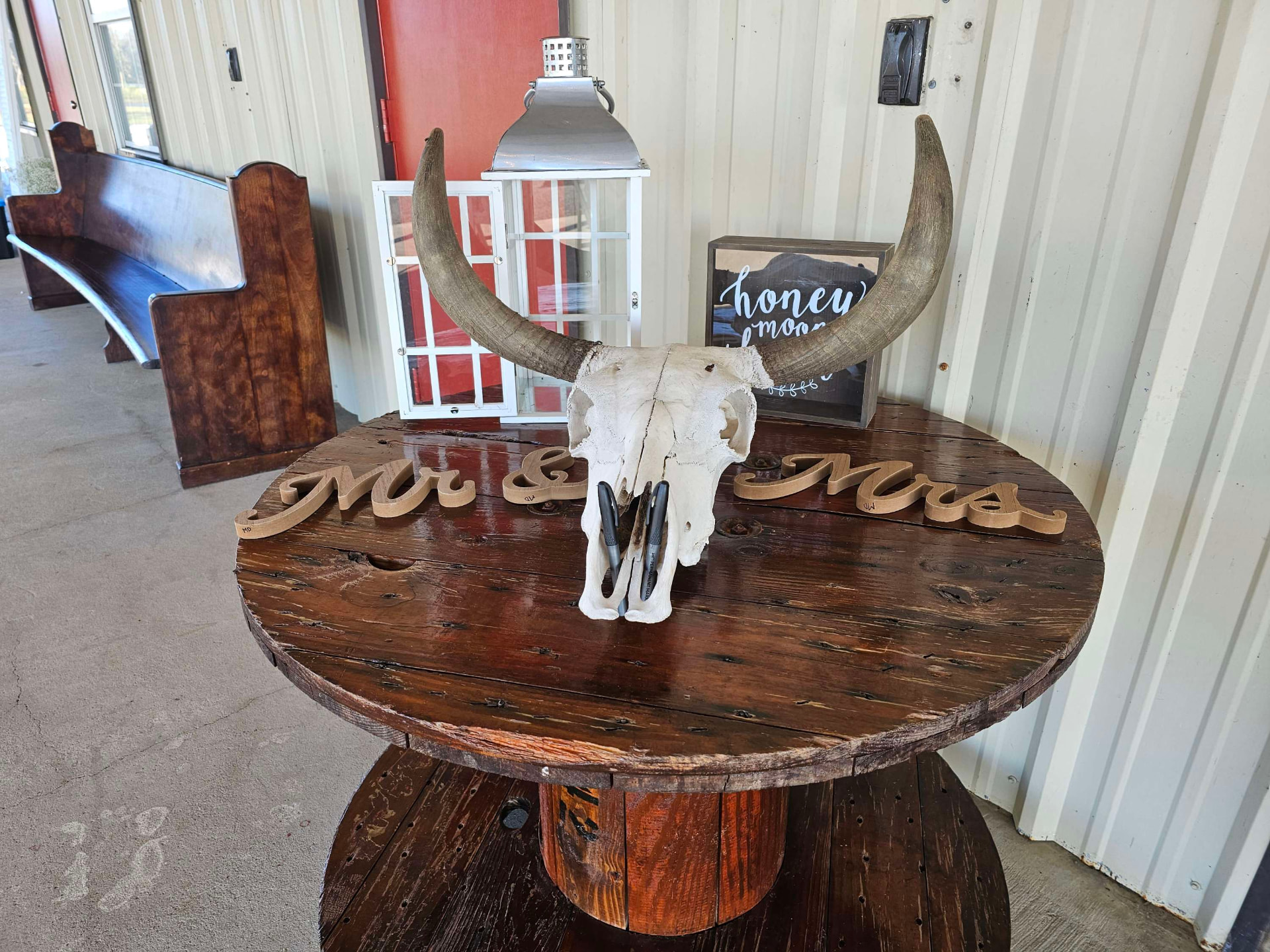 Mr and Mrs signs and a longhorn skull on a wooden spool table in the venue's decor collection at Reverie at Diamond D