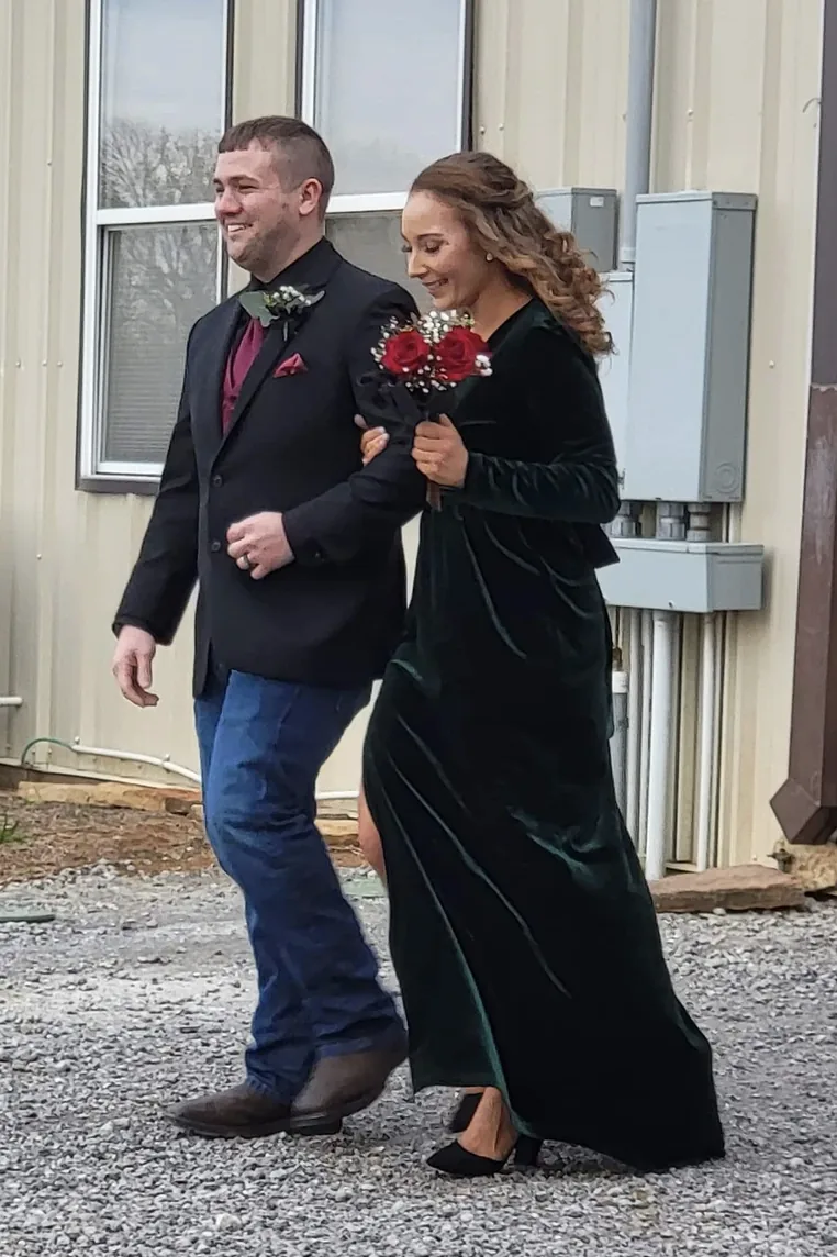 Bridesmaid in dark green velvet walking arm in arm with a groomsman at Reverie at Diamond D in Normangee, Texas