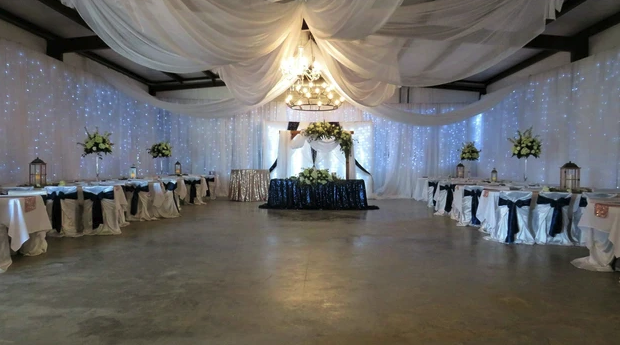 Barn reception with sequin head table, navy chair sashes and white ceiling draping