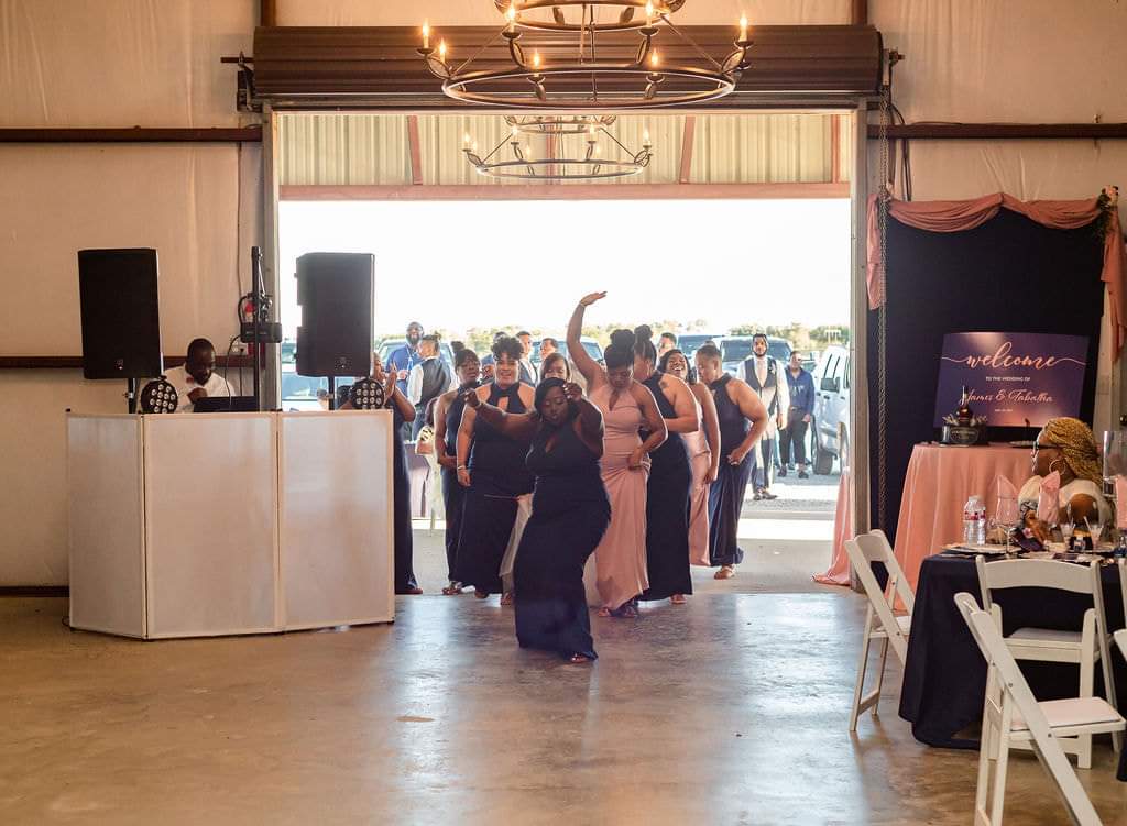 Wedding party dancing into the barn through the open roll-up door