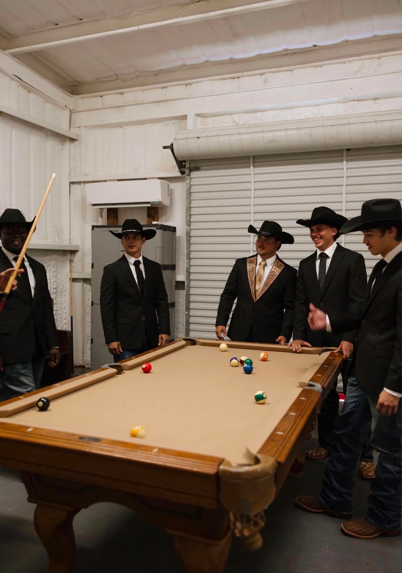 Groom and groomsmen in cowboy hats playing pool in the groom suite at Reverie at Diamond D