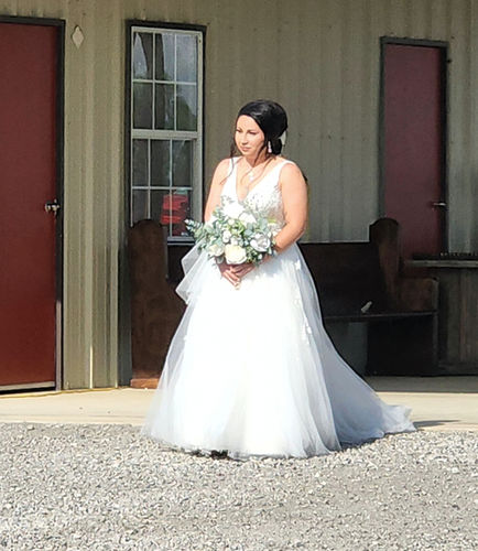 Bride with a white and eucalyptus bouquet outside the barn at Reverie at Diamond D