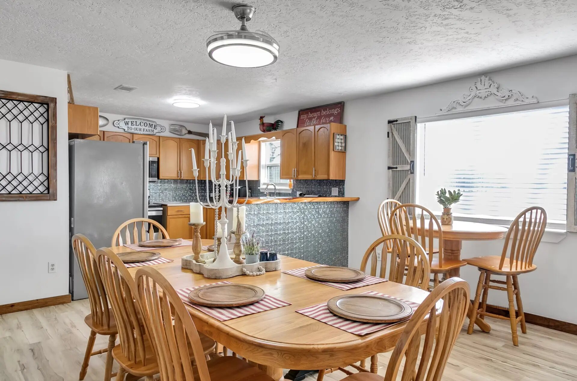 Farmhouse dining table set for eight with a candelabra centerpiece beside the kitchen bar at Reverie at Diamond D