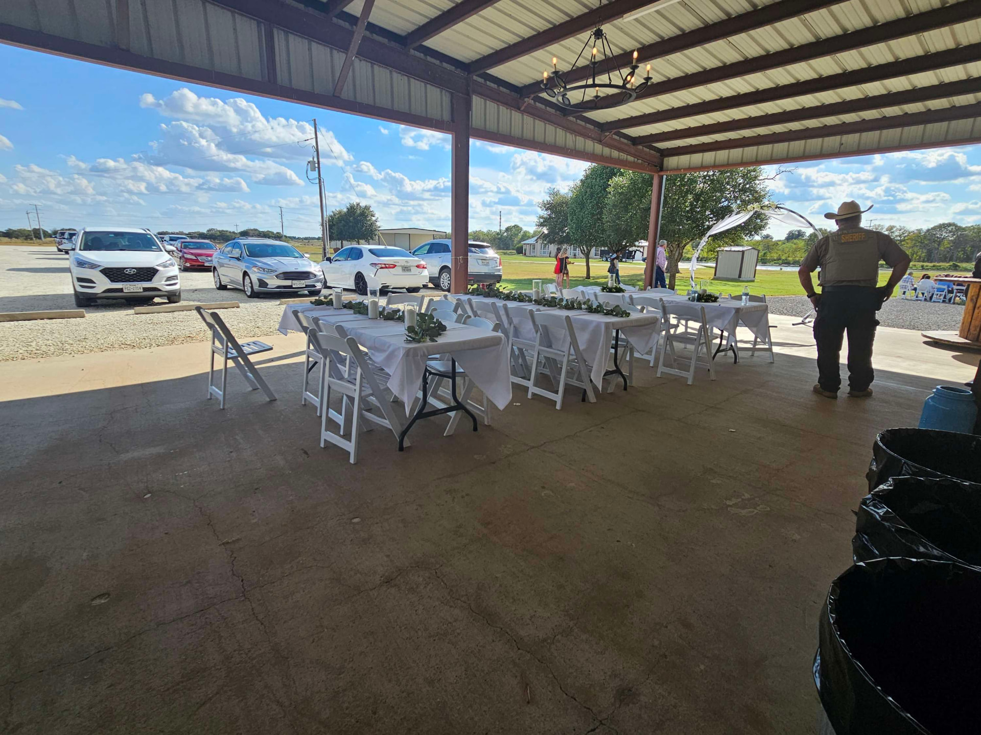 Covered patio dining tables set with white linens and greenery overlooking the grounds at Reverie at Diamond D