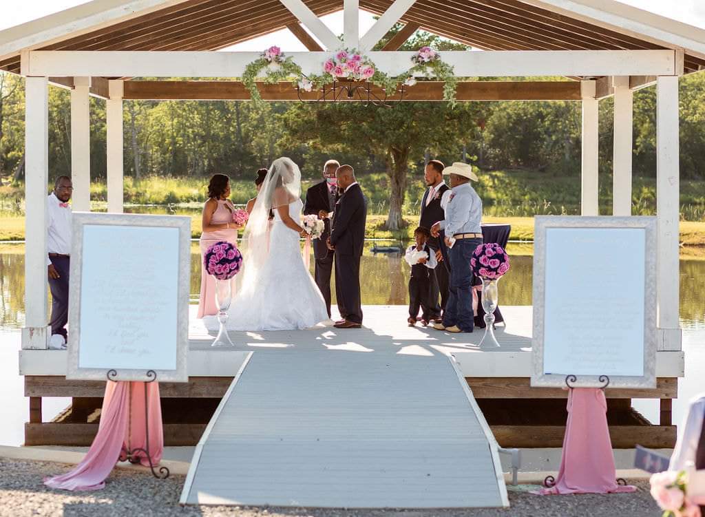 Wide view of the couple exchanging vows on the pavilion with the wedding party