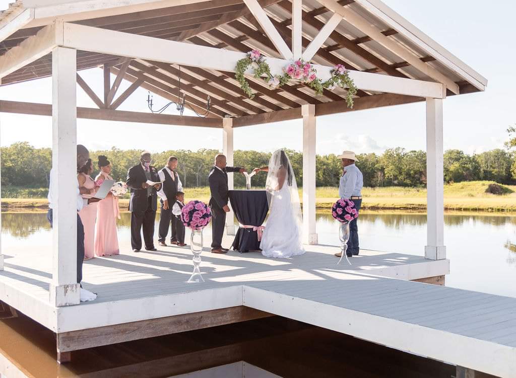 Wide view of the ceremony on the lakeside dock pavilion with the wedding party