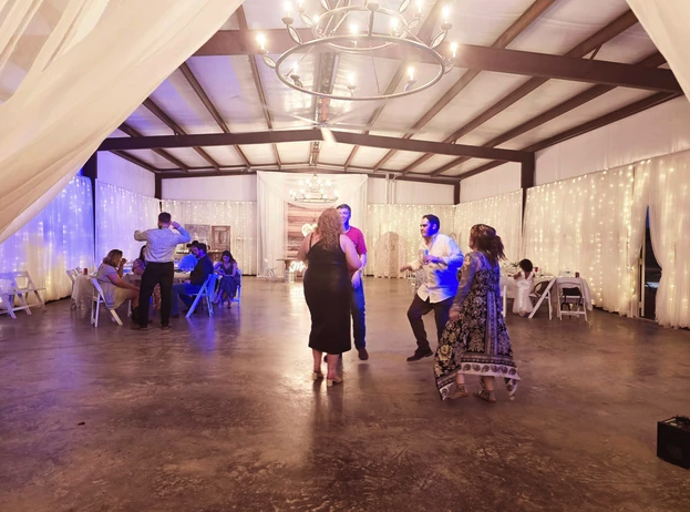 Guests dancing on the polished concrete floor under the barn chandelier and twinkle lights