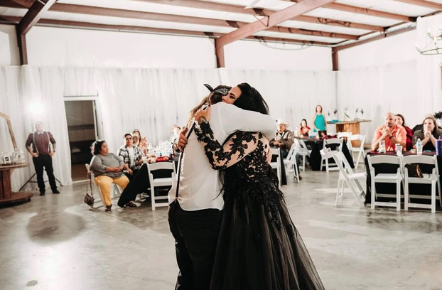 First dance in a black lace gown in the draped reception hall as guests look on