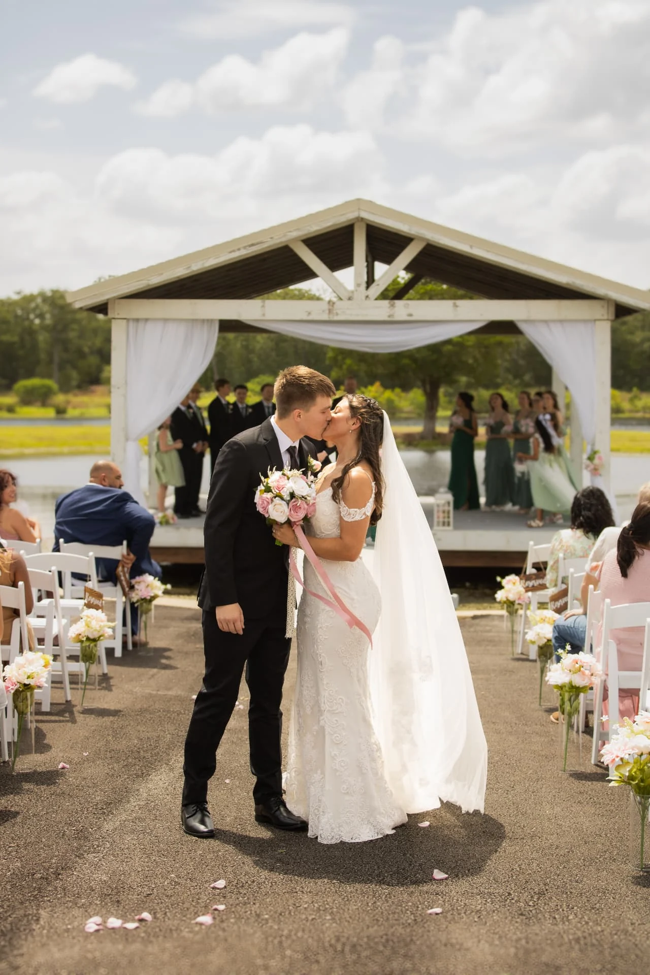 Bride and groom sharing their first kiss at the lakeside pavilion at Reverie at Diamond D in Normangee, Texas