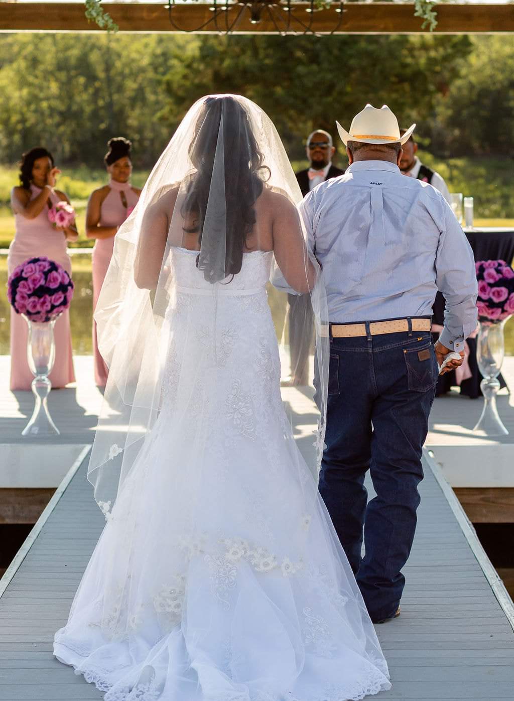 Bride escorted down the pavilion aisle by her father as bridesmaids look on