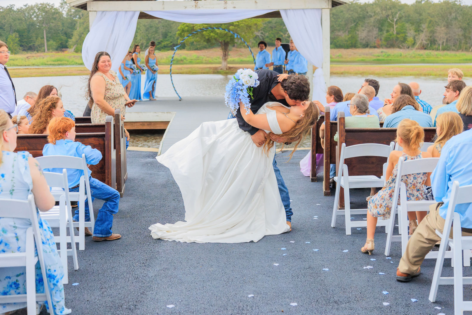 Jaelyn & Keelan's wedding at Reverie at Diamond D — the groom dips the bride for a kiss in the ceremony aisle with the lake behind them