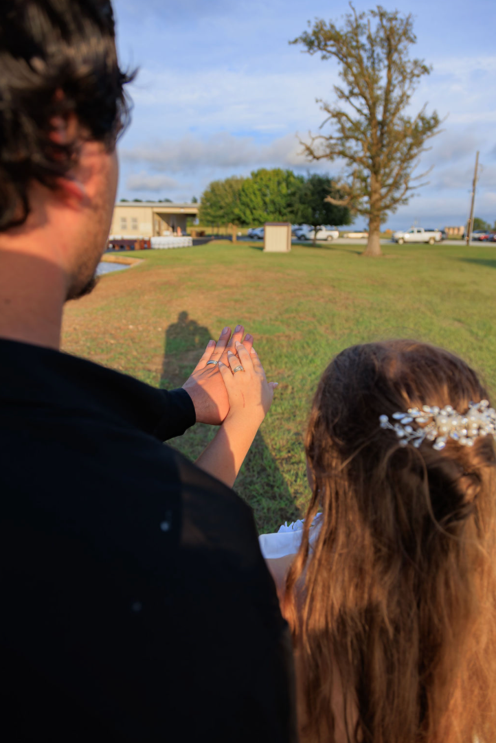 Jaelyn & Keelan's wedding at Reverie at Diamond D — the couple holding hands showing their rings, overlooking the grounds at golden hour