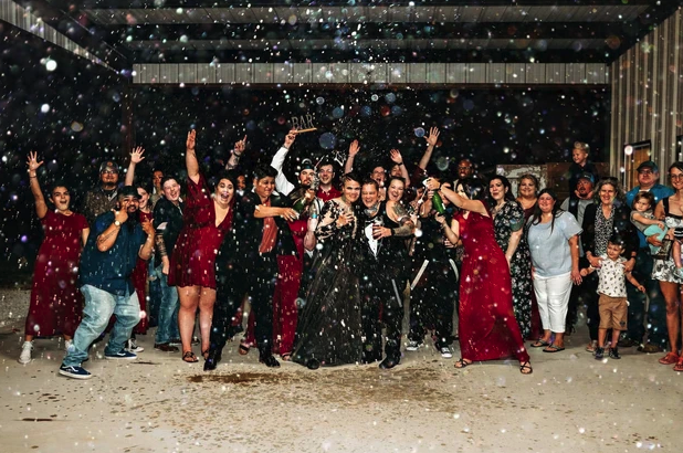 Candace and Chelsea surrounded by guests in a confetti and champagne send-off inside the pavilion