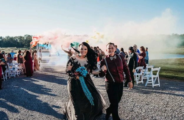 Colorful smoke bomb recessional as the newlyweds walk back up the lakeside aisle