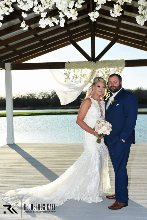 Bride and groom portrait under the lakeside pavilion with hanging white florals at Reverie at Diamond D
