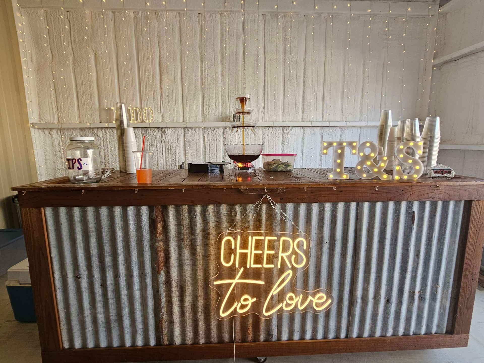 Rustic tin and wood bar with a Cheers to Love neon sign and marquee letters at Reverie at Diamond D