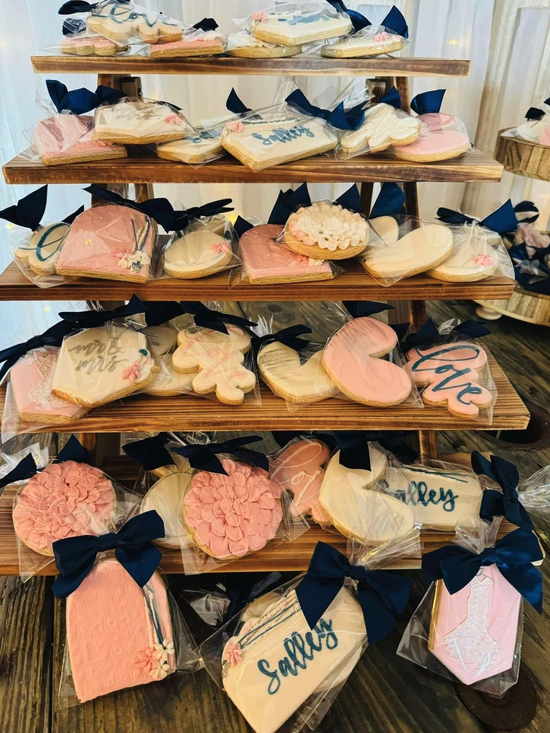 Tiered wooden display of blush and navy decorated cookie favors at a 2024 barn wedding reception