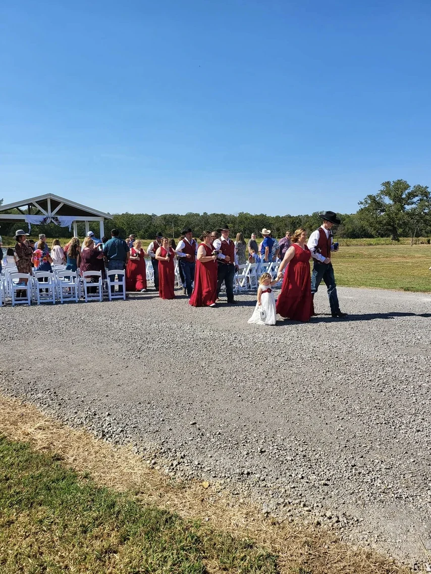 Wedding party and guests walking across the open ceremony lawn after an outdoor wedding near College Station, Texas