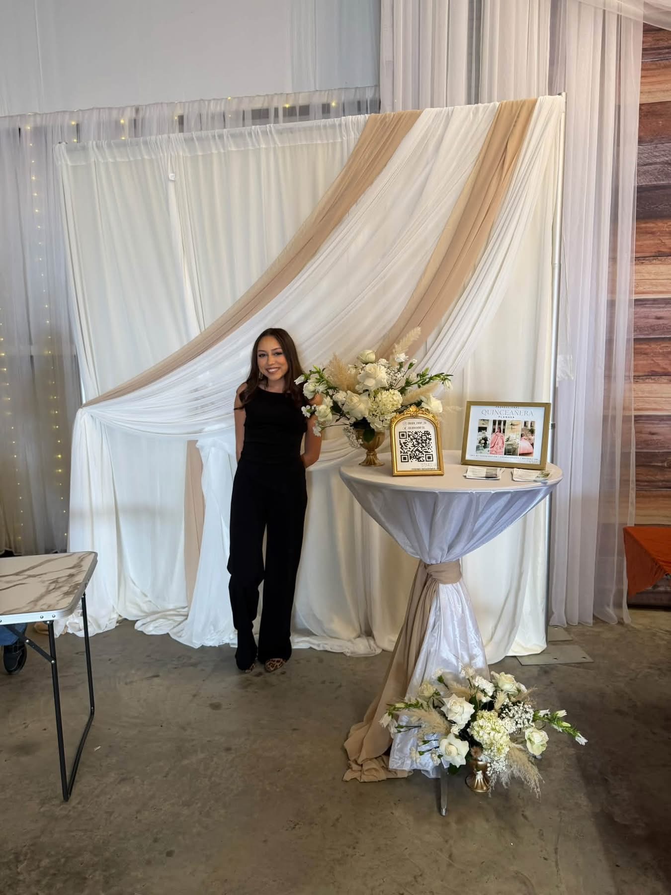 October 2026 Open House at Reverie at Diamond D wedding venue in Normangee, Texas — a vendor booth with champagne draping, white florals and a cocktail table