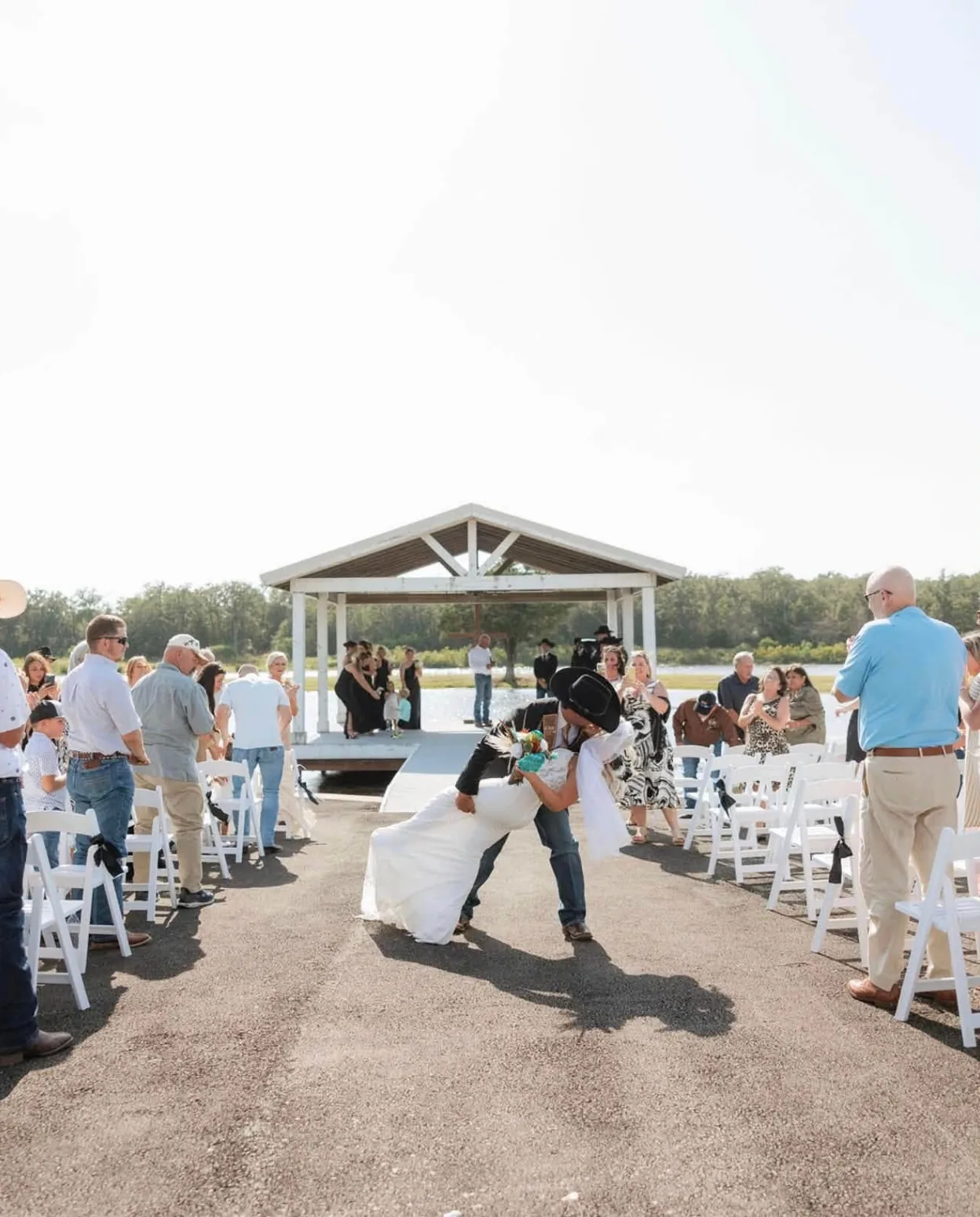 Groom dipping his bride for a kiss on the aisle after a lakeside ceremony at Reverie at Diamond D wedding venue in Normangee, Texas