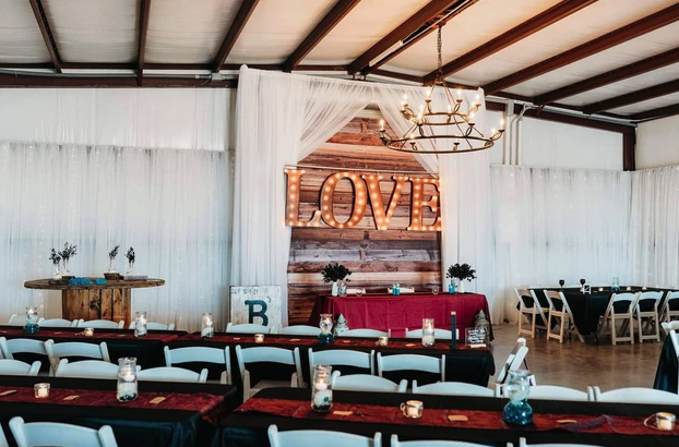 Reception hall set with burgundy runners, lanterns and the lighted LOVE marquee head table