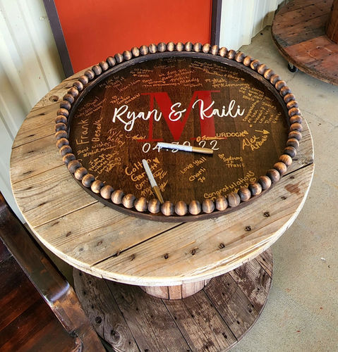 Wood monogram guest book on a spool table at a Reverie at Diamond D wedding