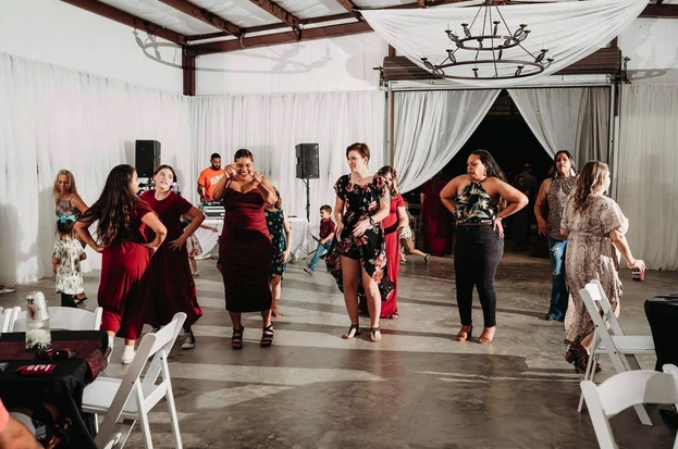Guests line dancing on the polished floor of the draped barn reception hall
