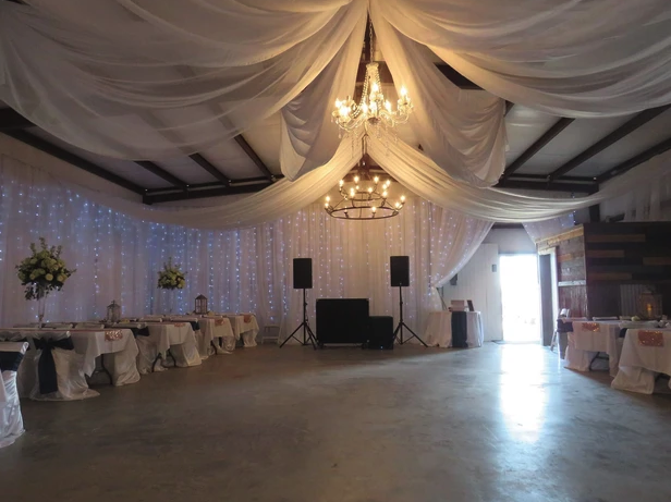 Barn dance floor with DJ booth, chandeliers and white ceiling draping